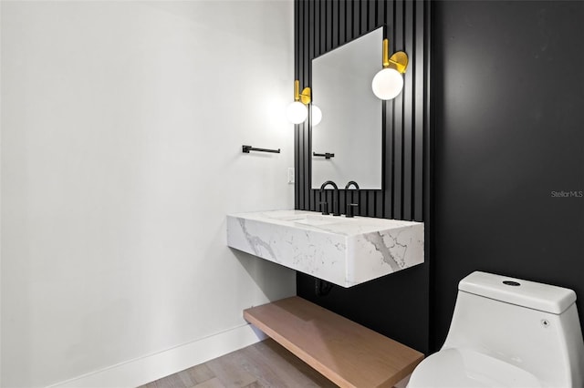 bathroom with wood finished floors, toilet, and baseboards