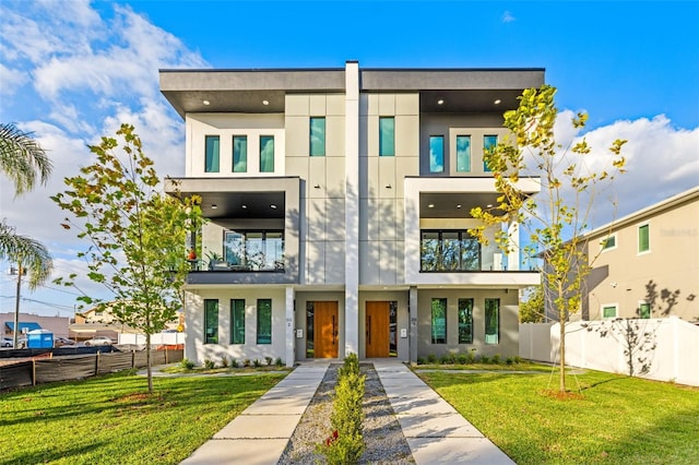 contemporary home with stucco siding, a front lawn, and fence