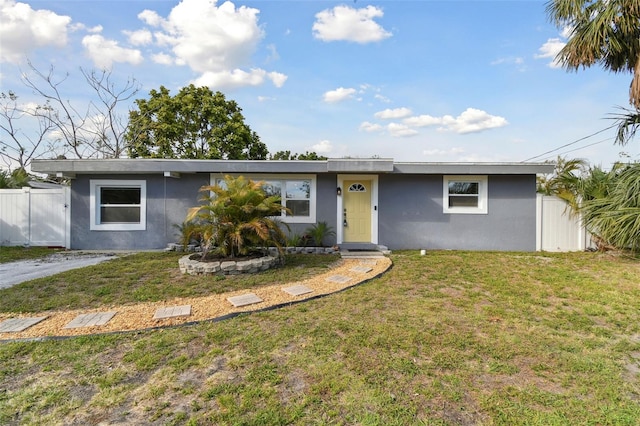 ranch-style home featuring a front yard, fence, and stucco siding