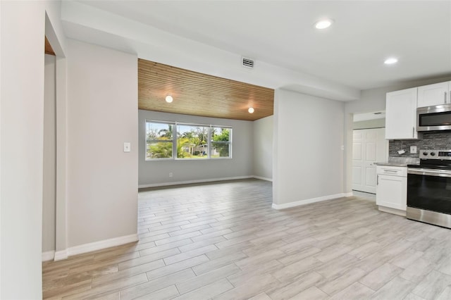 kitchen featuring appliances with stainless steel finishes, open floor plan, white cabinets, and decorative backsplash