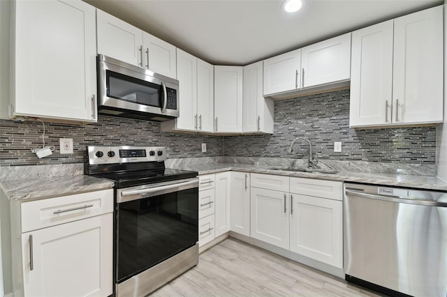 kitchen with stainless steel appliances, tasteful backsplash, a sink, and light stone counters