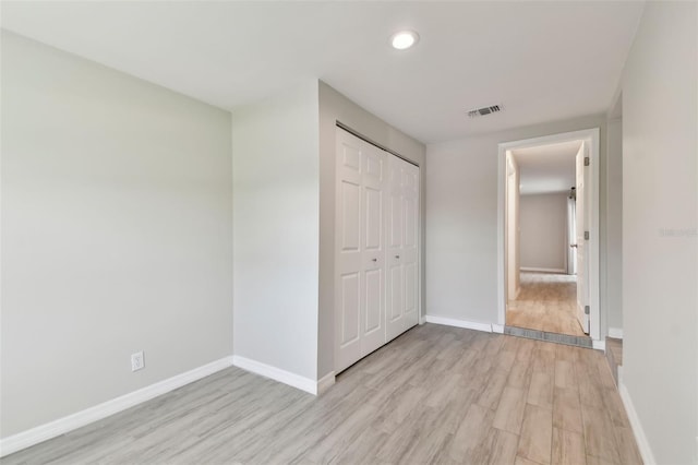 unfurnished bedroom with light wood-style flooring, a closet, visible vents, and baseboards