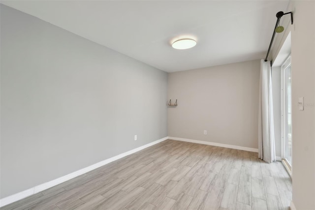 spare room featuring light wood-style floors and baseboards