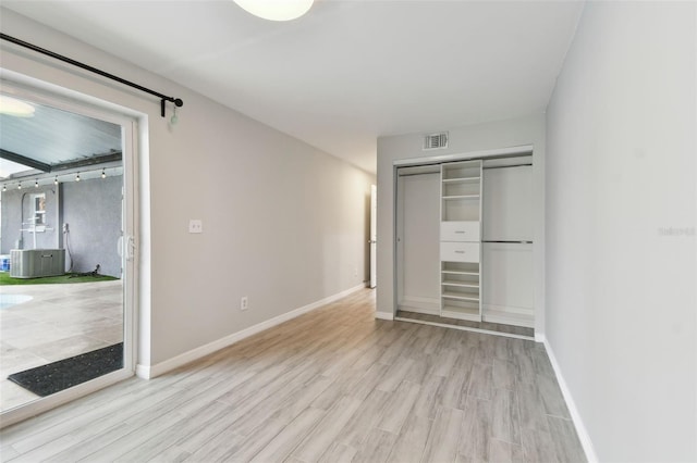 unfurnished bedroom featuring baseboards, visible vents, and wood finished floors