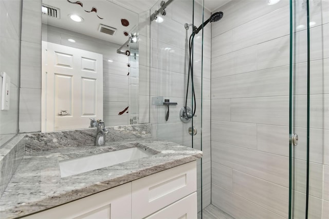 bathroom with a shower stall, visible vents, and vanity