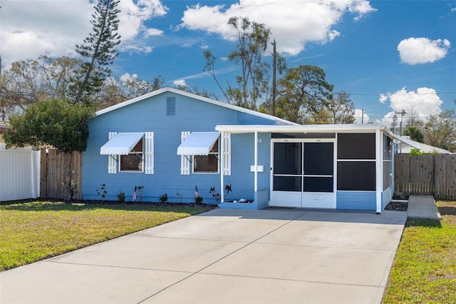 view of front of property with a sunroom, fence, and a front lawn