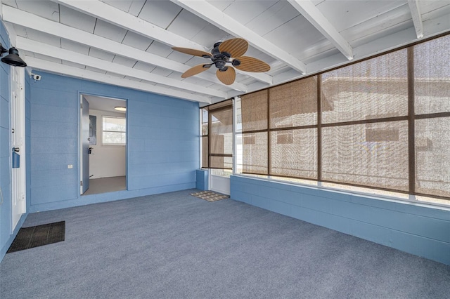 unfurnished sunroom featuring beamed ceiling and a ceiling fan