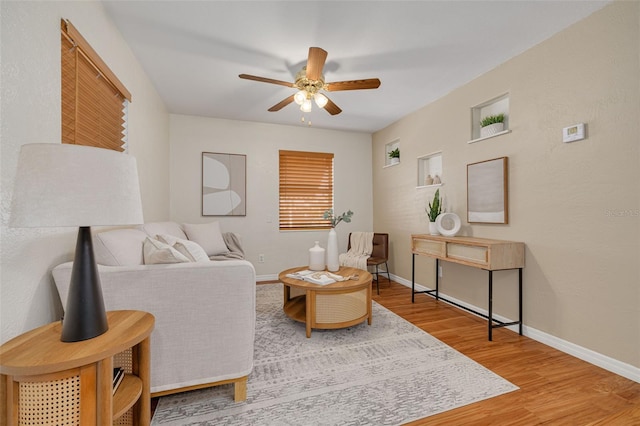 living room featuring ceiling fan, baseboards, and wood finished floors