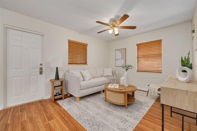 living area with light wood-type flooring, ceiling fan, and baseboards