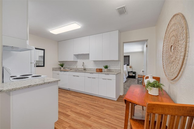 kitchen with visible vents, modern cabinets, white dishwasher, a sink, and exhaust hood