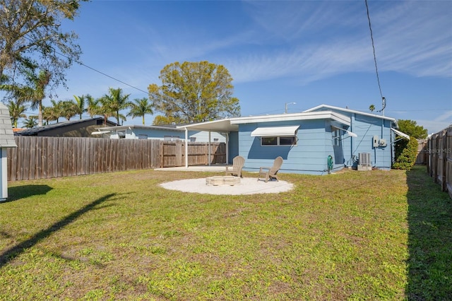 rear view of house featuring a fire pit, a fenced backyard, a yard, central air condition unit, and a patio area