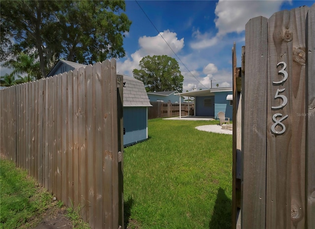 view of yard with an outbuilding, a storage shed, a patio area, and fence