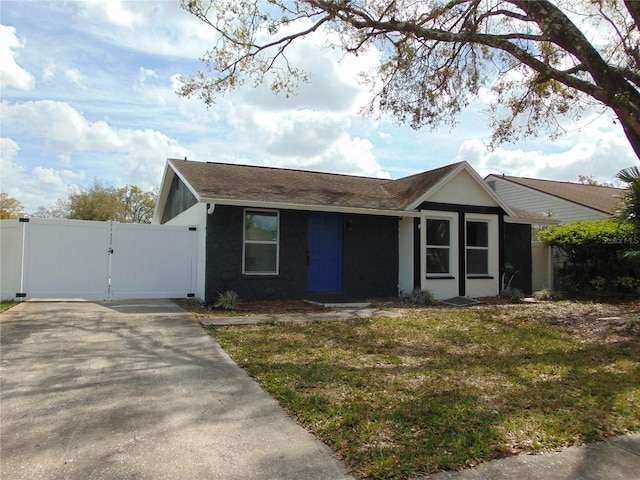 ranch-style home featuring a front yard, a gate, and stucco siding