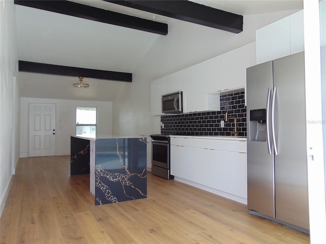 kitchen featuring stainless steel appliances, tasteful backsplash, white cabinetry, light wood-type flooring, and beamed ceiling