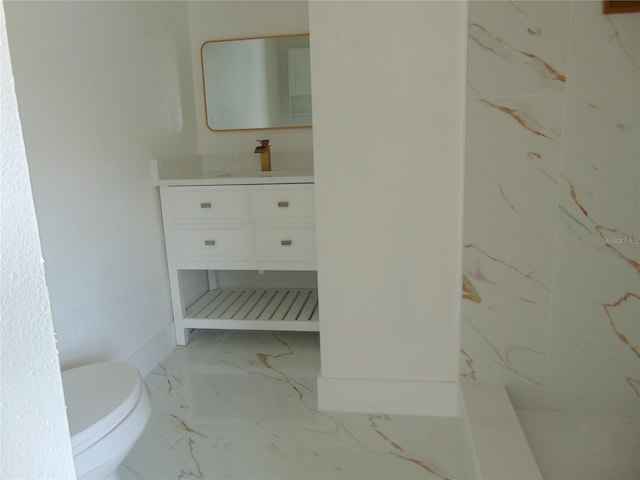 bathroom featuring toilet, marble finish floor, and vanity