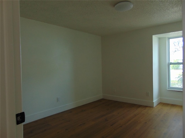 unfurnished room with a textured ceiling, wood finished floors, and baseboards