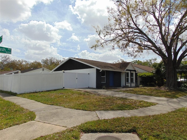 view of side of property with a yard, an attached garage, a gate, fence, and driveway