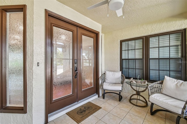 entrance to property featuring stucco siding, french doors, and a ceiling fan