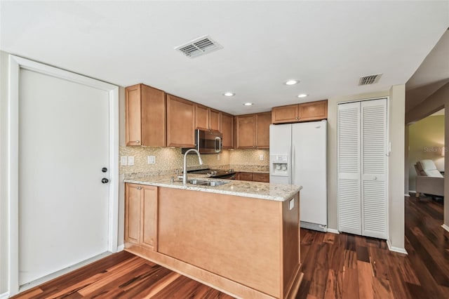 kitchen featuring visible vents, dark wood finished floors, appliances with stainless steel finishes, a peninsula, and a sink