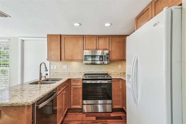 kitchen featuring a sink, decorative backsplash, appliances with stainless steel finishes, and a peninsula