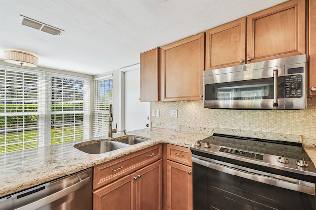 kitchen with light stone counters, visible vents, a sink, stainless steel appliances, and tasteful backsplash