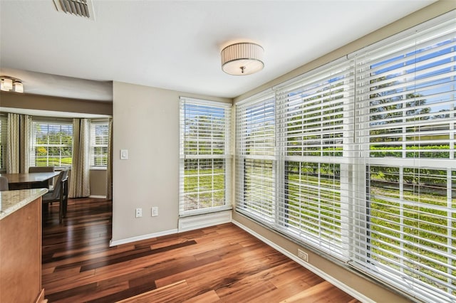 unfurnished dining area with visible vents, baseboards, and wood finished floors