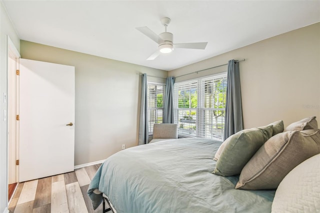 bedroom featuring a ceiling fan, baseboards, and light wood finished floors