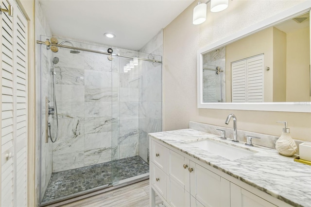 bathroom with a marble finish shower, vanity, and a closet