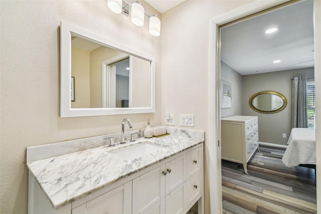 bathroom with vanity, recessed lighting, wood finished floors, and baseboards