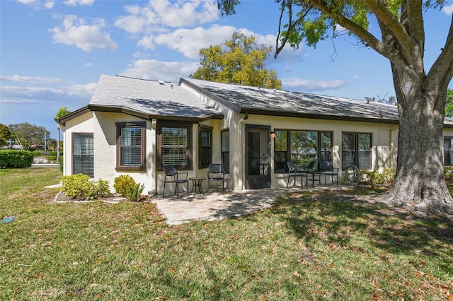 back of house featuring a patio area, stucco siding, a yard, and roof with shingles