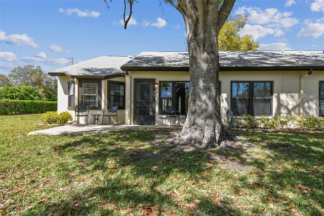 rear view of property with a yard, a patio, and stucco siding