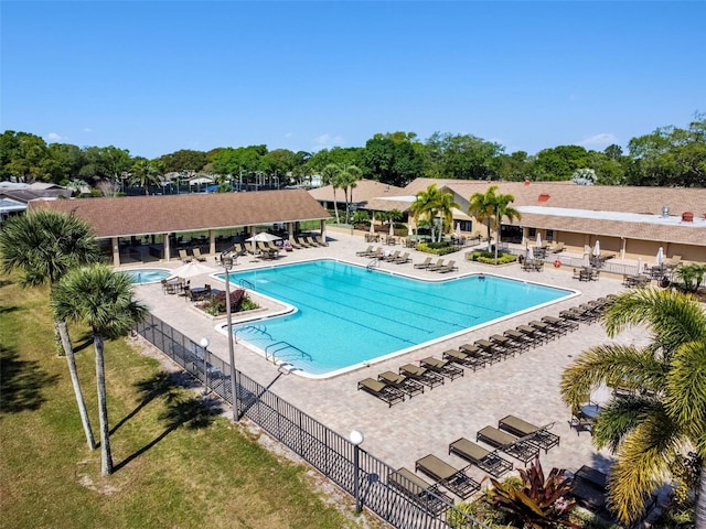 pool with a patio, a lawn, and fence