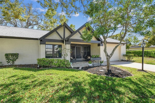 english style home with stucco siding, driveway, a front lawn, an attached garage, and a sunroom