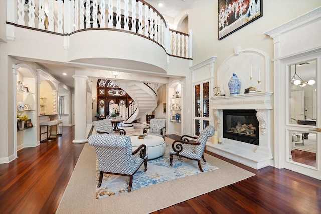 living room featuring stairs, a fireplace, ornate columns, and wood finished floors