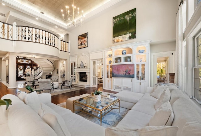 living room with a raised ceiling, a fireplace with raised hearth, a towering ceiling, wood finished floors, and a chandelier