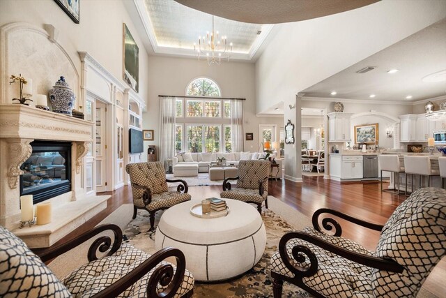 living room with visible vents, dark wood-style floors, an inviting chandelier, crown molding, and a high end fireplace