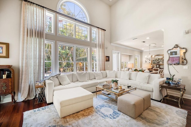 living area with baseboards, a high ceiling, wood finished floors, and a healthy amount of sunlight