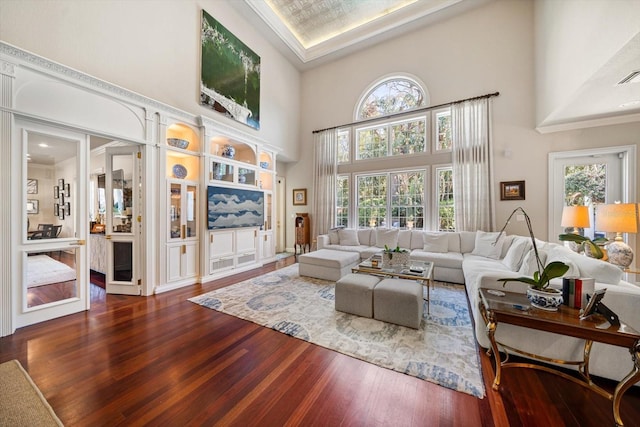 living room featuring visible vents, a towering ceiling, and wood finished floors