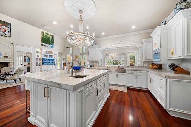 kitchen featuring stainless steel microwave, a sink, a notable chandelier, and white cabinetry