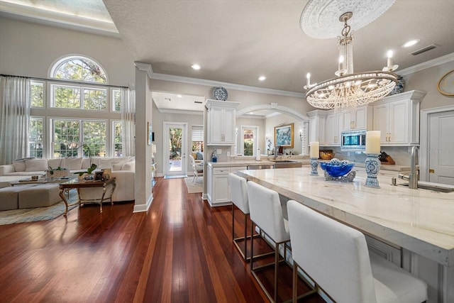 kitchen featuring stainless steel microwave, visible vents, open floor plan, white cabinetry, and a sink