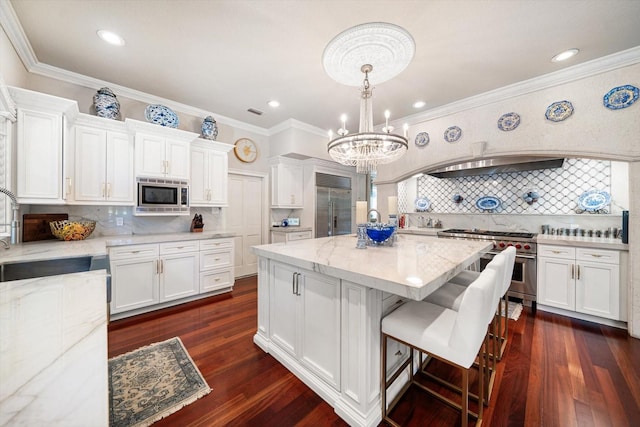 kitchen featuring light stone countertops, a center island, white cabinetry, and built in appliances