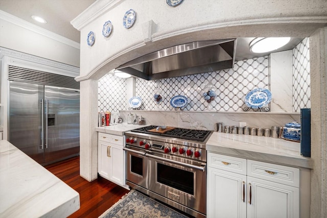 kitchen with tasteful backsplash, white cabinets, high end appliances, dark wood-type flooring, and crown molding