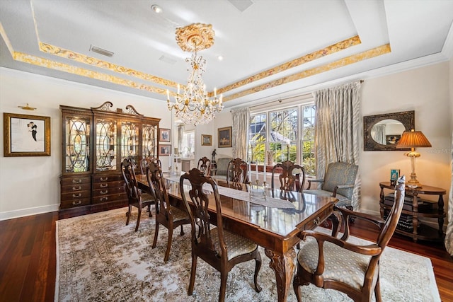 dining room featuring a tray ceiling, visible vents, an inviting chandelier, wood finished floors, and baseboards