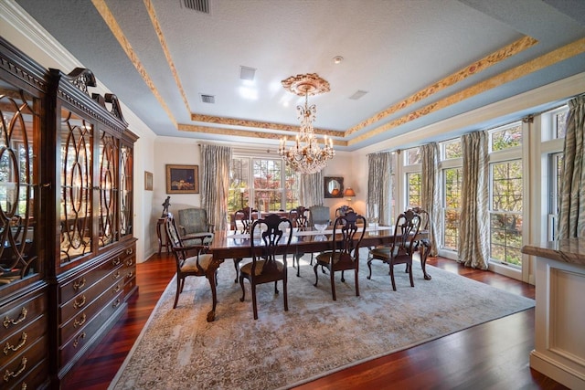 dining room featuring visible vents, dark wood finished floors, a raised ceiling, ornamental molding, and a notable chandelier