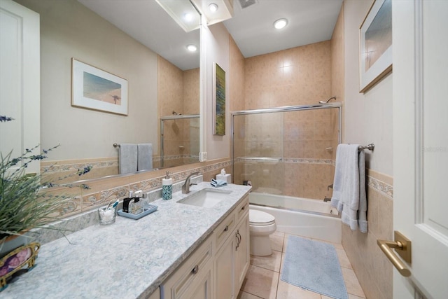 full bathroom featuring enclosed tub / shower combo, toilet, tile walls, vanity, and tile patterned floors