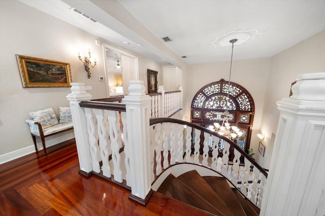 stairway featuring a chandelier, visible vents, baseboards, and wood finished floors