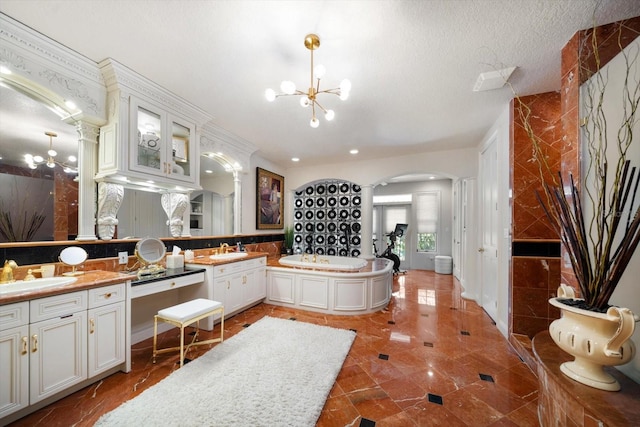 bathroom with a garden tub, a notable chandelier, a textured ceiling, and vanity