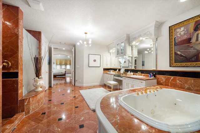 bathroom featuring a notable chandelier, connected bathroom, a textured ceiling, vanity, and a jetted tub