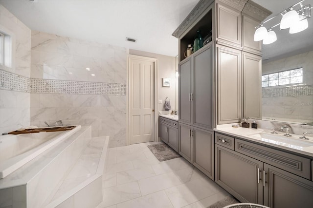 full bathroom with visible vents, marble finish floor, a garden tub, and vanity