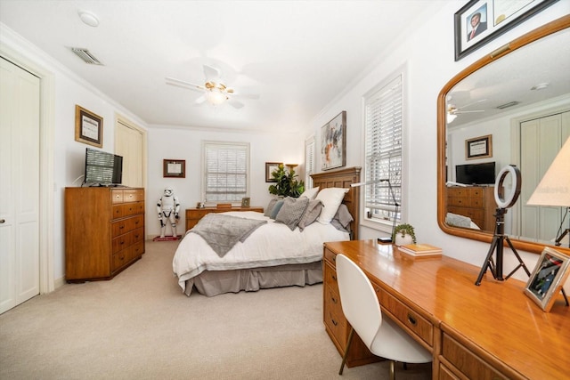 bedroom featuring ceiling fan, visible vents, crown molding, and light colored carpet